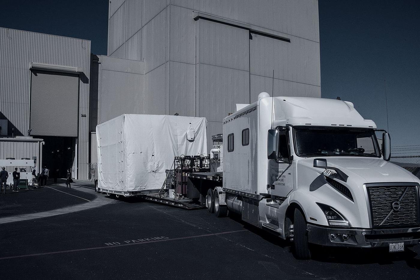 A sleeper cab tractor backed into a warehouse dock during loading.